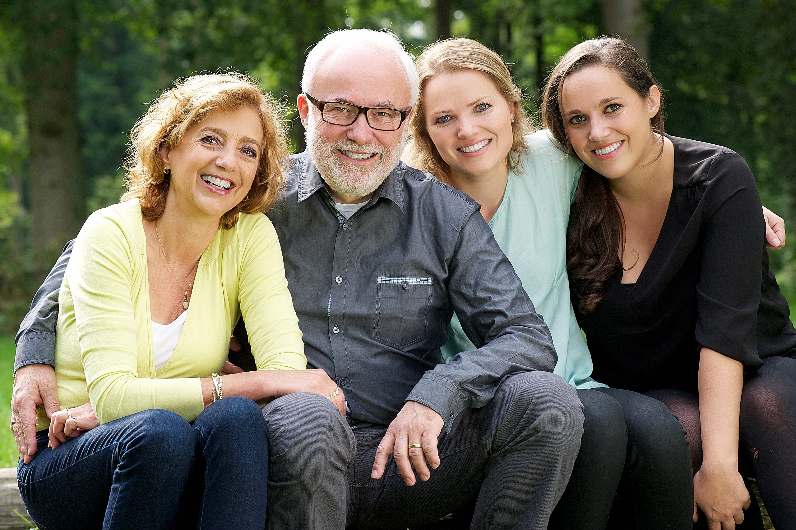 Portrait of a happy family with mother father and two daughters smiling in park setting Portrait of a happy family with mother father and two daughters smiling in park setting